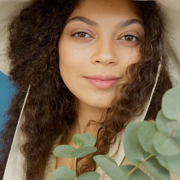 Smiling person stretching outdoors with a green natural background.